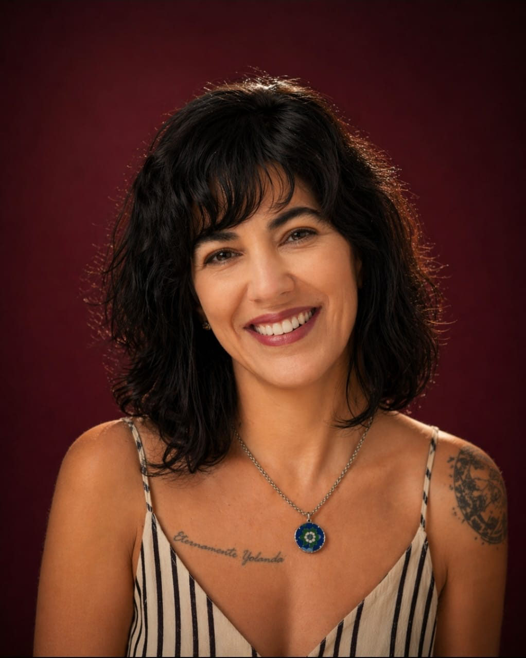 Retrato de Juliana Marra sorrindo, sobre fundo vinho